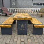 Koka piknika galda un solu komplekts ar metāla kājām uz bruģēta laukuma