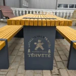 Koka āra galds ar diviem soliem un Tērvetes dabas parka logo uz metāla kājas
