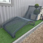 Pelēks metāla šezlongs dārza terasei