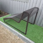 Brūns metāla šezlongs ar taisnu rāmi skatīts no aizmugures