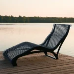 Metāla šezlongs uz koka laipas pie ezera krasta