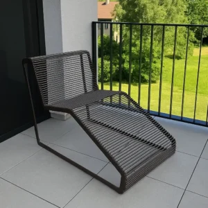 Brūns metāla šezlongs uz balkona ar skatu uz zaļu pagalmu