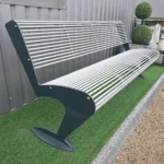 Metāla stienīšu sols ar pelēkām kājām tuvplānā pie ēkas