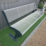 Pelēks metāla sols ar baltiem metāla stienīšiem pie ēkas fasādes