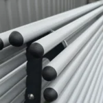 Metāla caurulīšu sola tuvplāns ar melniem plastmasas korķīšiem un rasas pilieniem