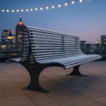 Metāla caurulīšu sols ar plastmasas korķīšiem uz jumta terases vakarā