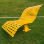 Dzeltenais viļņotais metāla dārza sols parkā uz zāliena