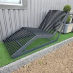 Metāla atpūtas sols pie industriālas ēkas sienas