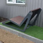 Metāla atpūtas sols ar koka sēdvirsmu pie ēkas, slīps skatupunkts