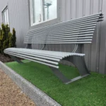 Metāla sols pie ēkas fasādes uz mākslīga zāliena